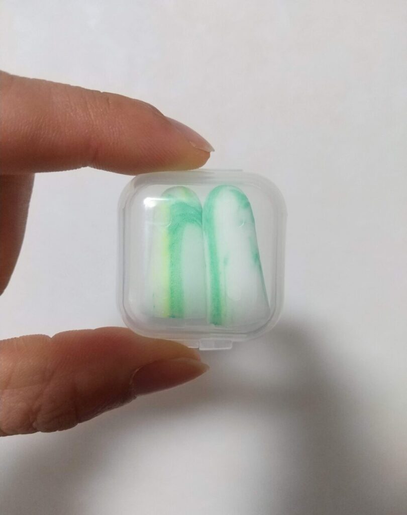 透明なケースに入れられた、緑と白のマーブル模様の耳栓の写真