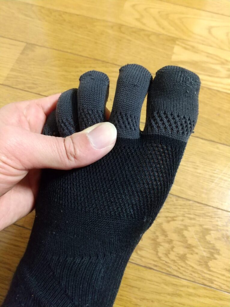 Tabioレーシングラン五本指を履いた状態で、足の指の部分を手で触っている写真