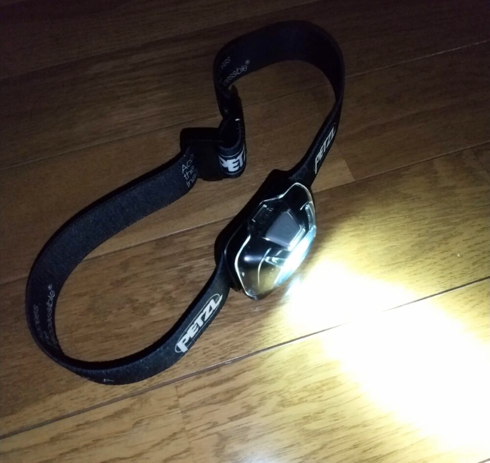 PETZL（ペツル）のヘッドライト「ティカ（黒）」を床に置いた状態で点灯させた写真