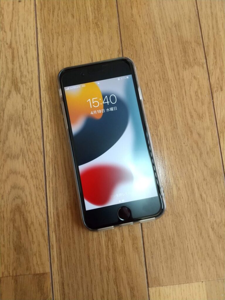 「iPhone SE」を木の床に置いた写真
