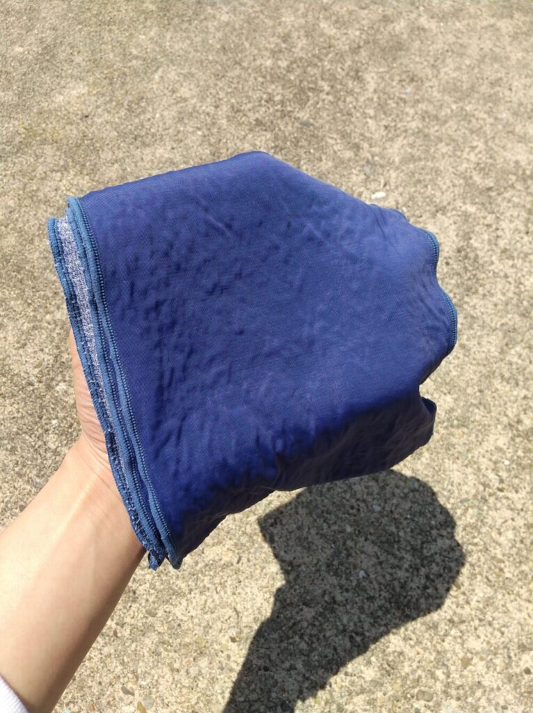 水で濡らした青色の冷却タオルを手に持っている写真