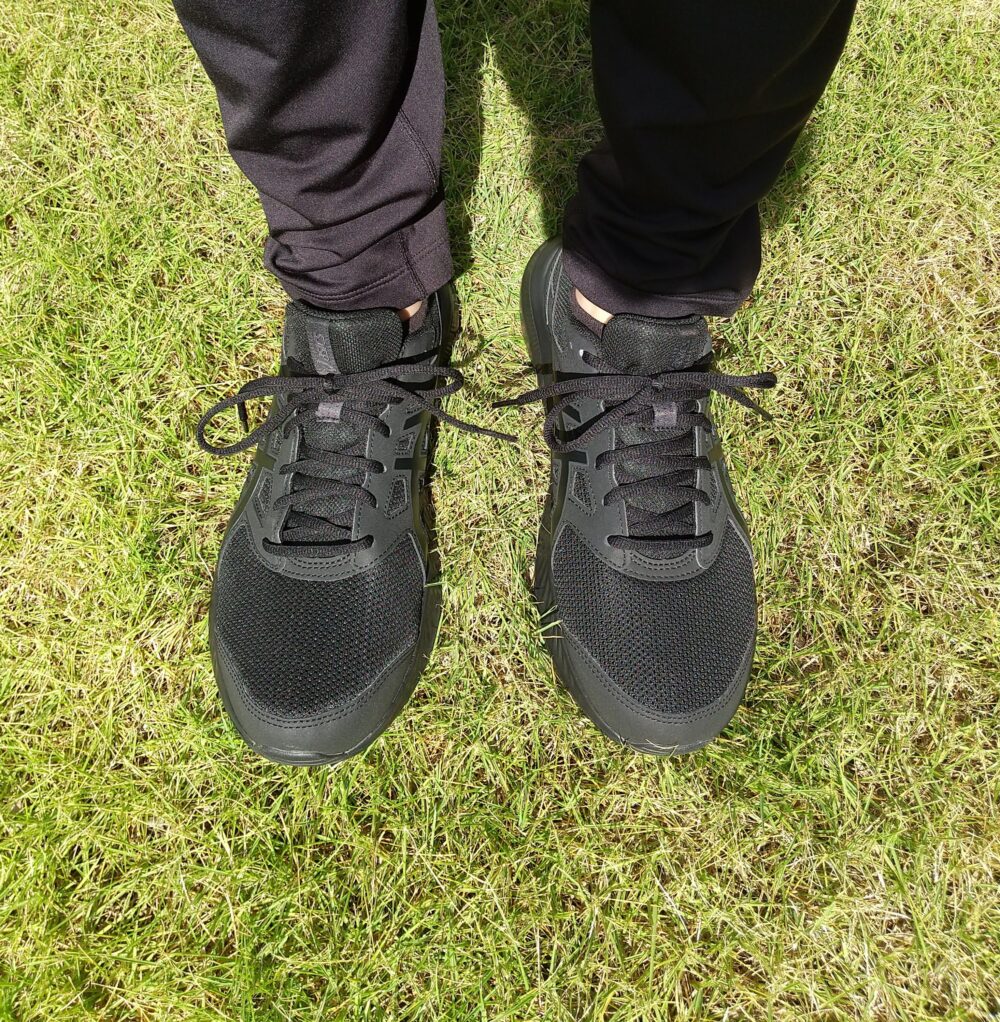 アシックスのJOLT４（黒色）を履いて芝生の上に立っている写真