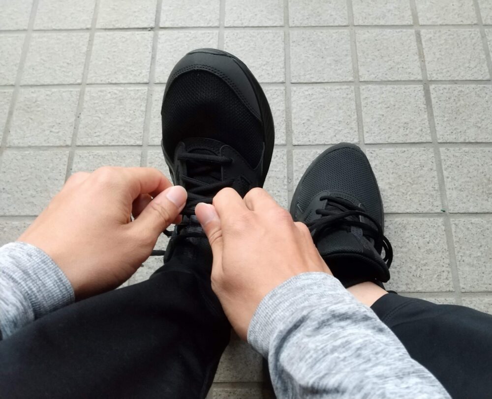 黒色のランニングシューズを履いて靴紐を結んでいる写真