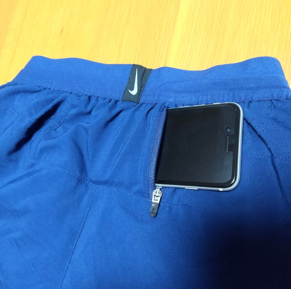 腰にジッパー付きポケットが備わったナイキのランニングパンツ（青色）にスマホを収納しようとしている写真